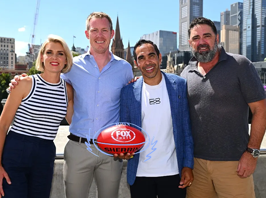A group photo of Fox Footy hosts Sarah Wilson, Jack Riewoldt, Eddie Betts and Gary Lyon on Melbourne’s Yarra River. Eddie Betts holds a red Sherrin Football. Image Credit: TV Tonight