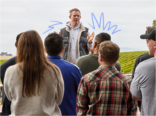 Jack Riewoldt speaks to a group of people on an Authentic Leaders Group immersion. There are vineyards in the background.