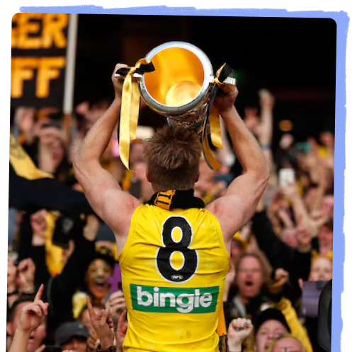 Jack Riewoldt holding the AFL premiership cup. He wears his yellow guernsey number eight, and is facing a celebratory crowd. Image Credit: AFL Media, Michael Wilson.