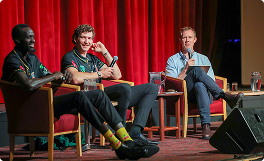 Jack Riewoldt emceeing a discussion panel with Tasmania JackJumpers. He wears a blue shirt.